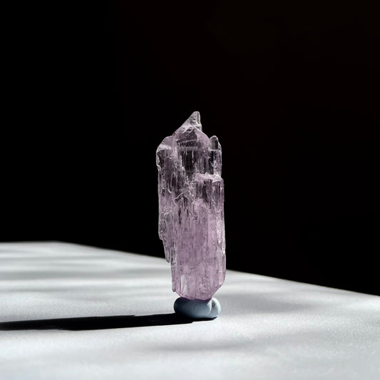 
High-quality gem-grade raw Kunzite specimen, displaying vibrant pink to lilac tones with exceptional clarity and brilliance. The specimen's well-formed prismatic structure and smooth, polished facets highlight its premium quality and luminous, glassy appearance.